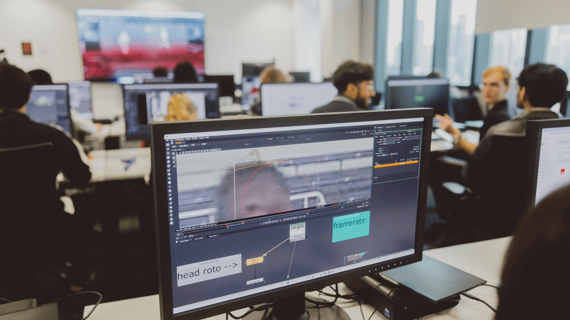 People working at desks with computer screens displaying video editing software.