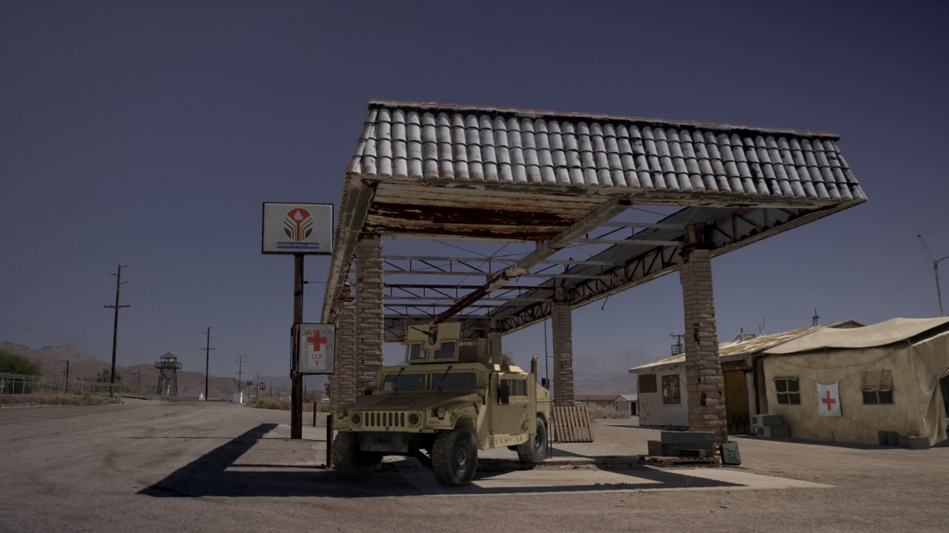 Abandoned gas station with a military vehicle and medical tent under a clear sky.