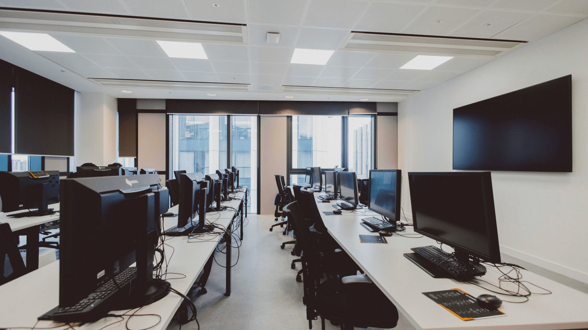An Escape classroom with rows of computers and a screen on the wall.
